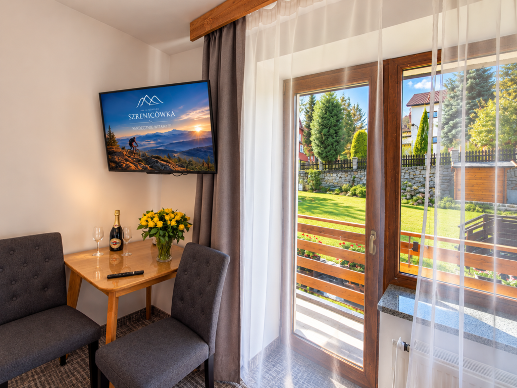 Zimmer Kamieńczyk – Tisch mit Stühlen und Balkontür mit Gartenblick