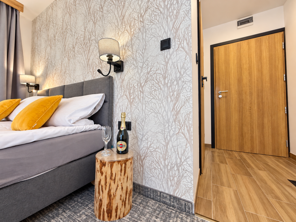 Zimmer Kamieńczyk – Bett, Nachttischlampe und Zimmereingang