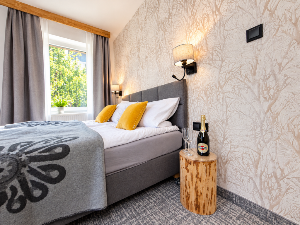 Zimmer Kamieńczyk – Bett mit gelben Kissen und Nachttischlampen